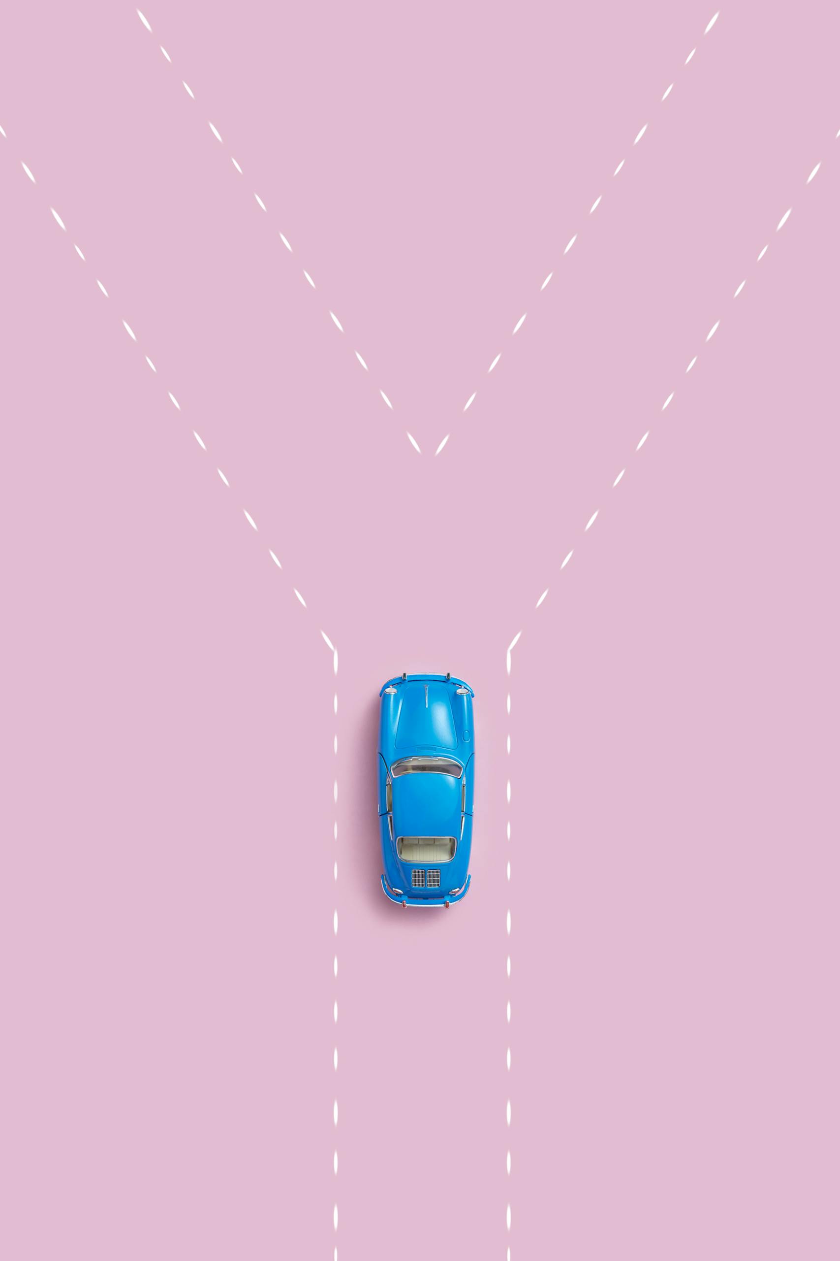 Aerial view of a blue car on a pink background symbolizing a fork in the road.